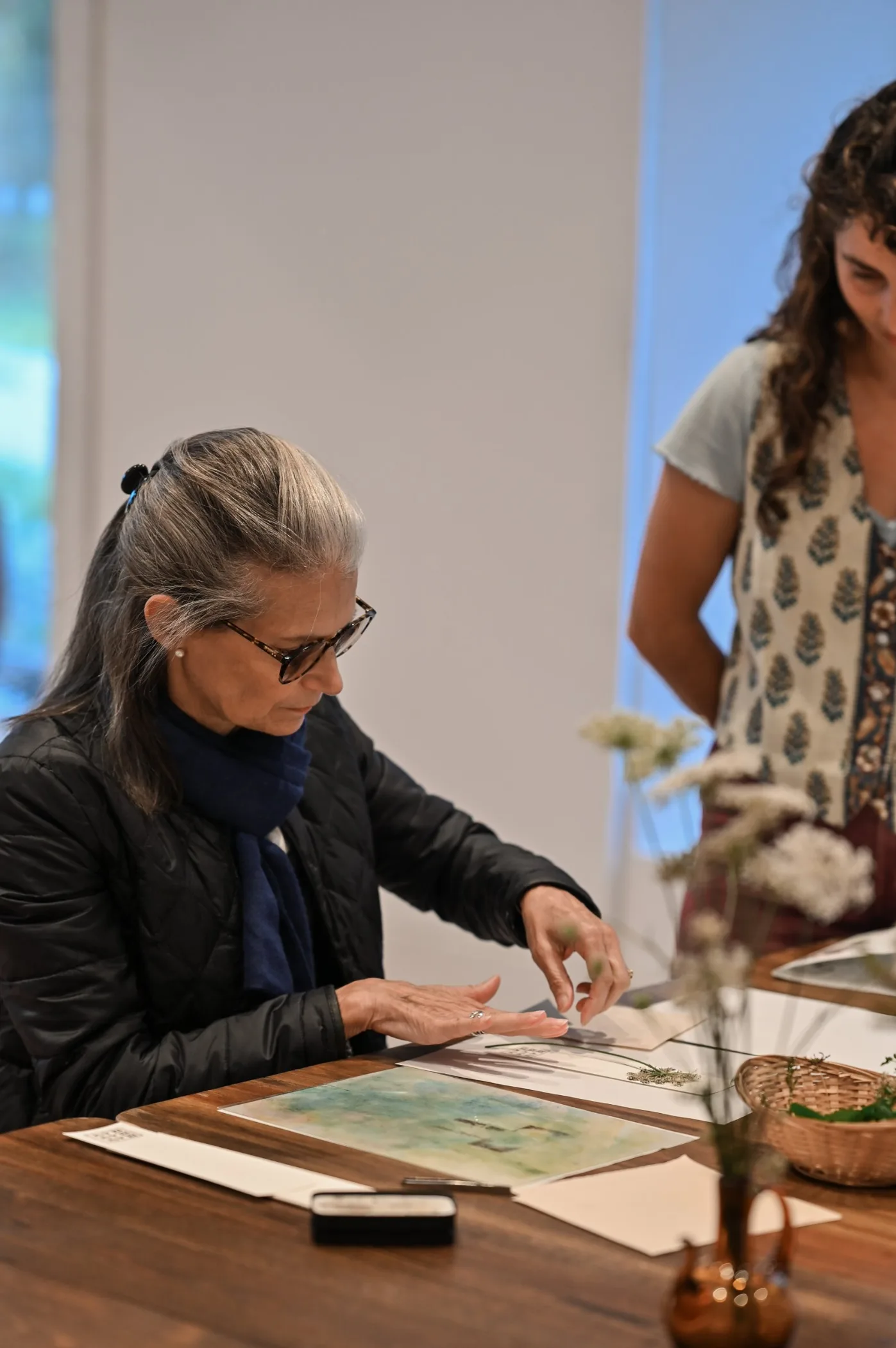 Une participante réalise une empreinte végétale à la table de l’atelier de la Manufacture du Blanc, accompagnée par une artisane