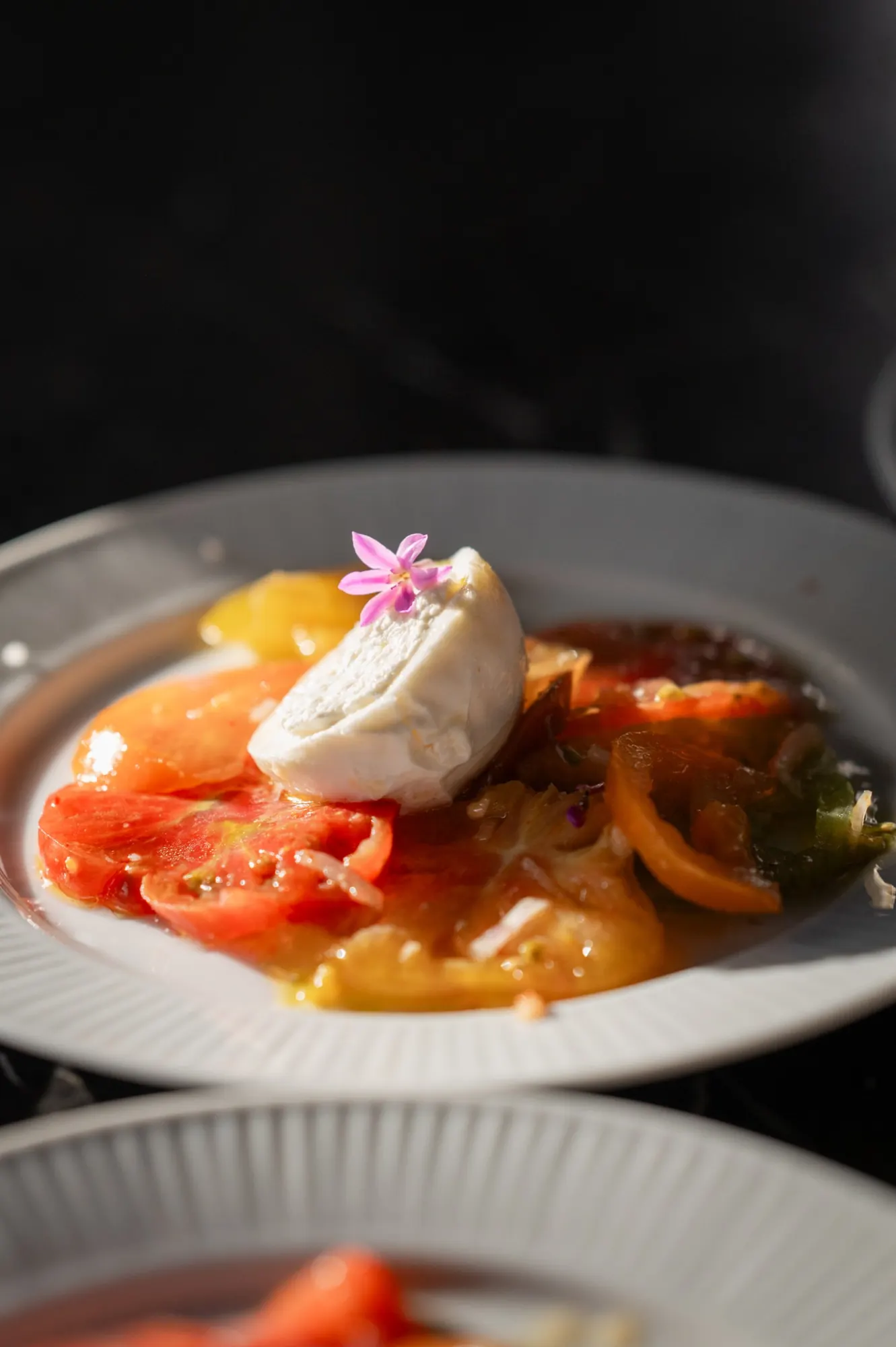 A heirloom tomato and burrata with a pink flower
