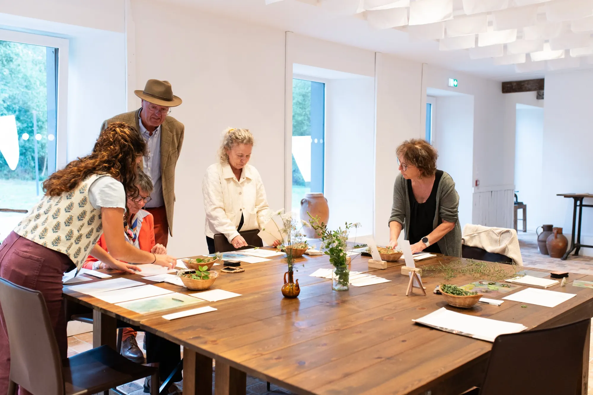 A group of guests laying plants and paper on a long wooden workshop table