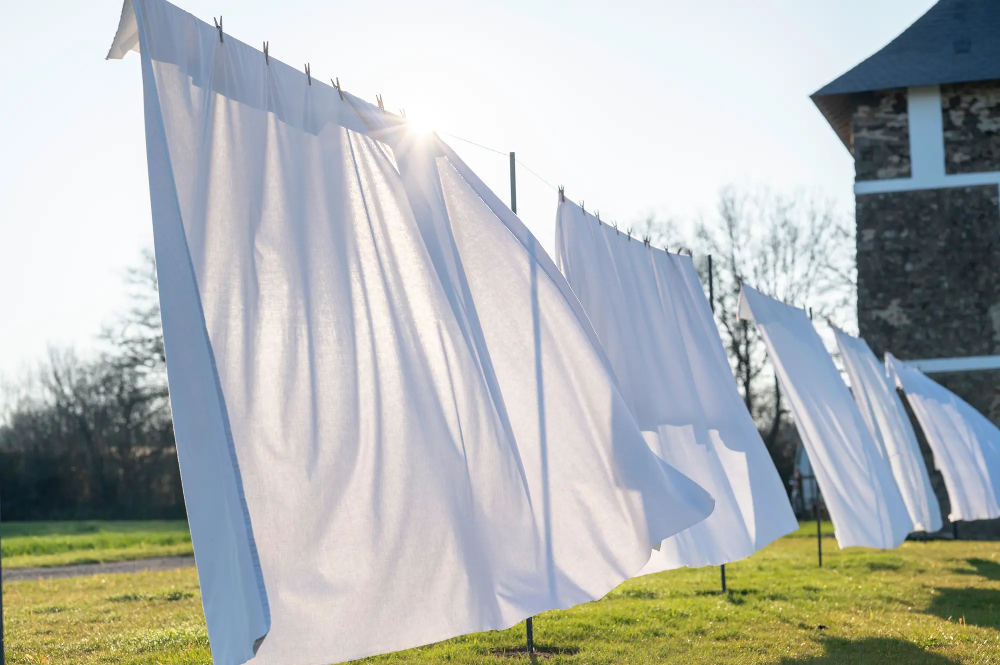 White linen drying in the wind on the lawn in front of the stone house