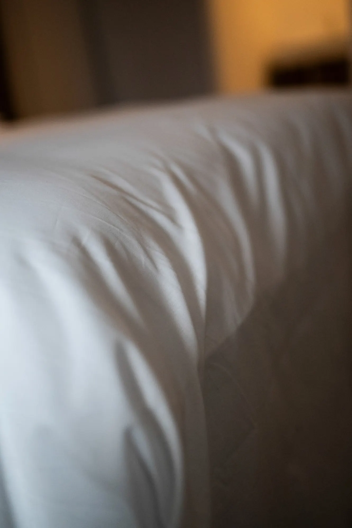 The edge of a white linen bed sheet