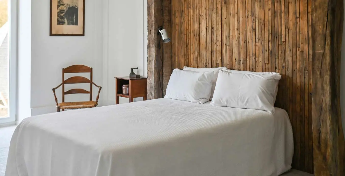 Chambre du Teinturier avec lit blanc et mur en vieux bois