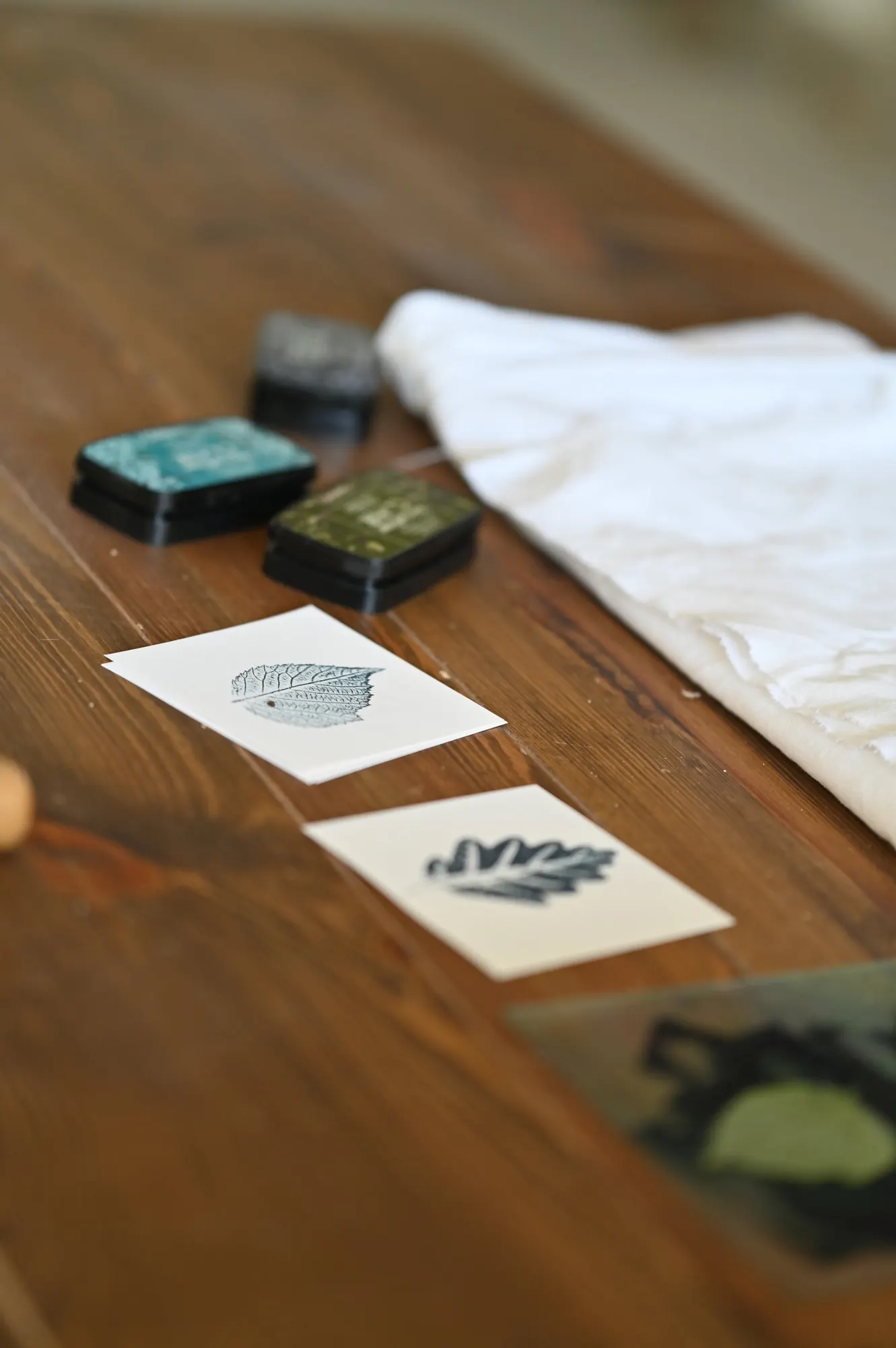 Leaf impressions printed on cards, with ink pads and linen on a table